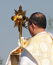 The Blessed Sacrament in a monstrance carried in a procession by a priest wearing a humeral veil HoldingMonstrance.jpg