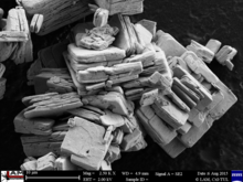 Electron micrograph of lamellar particles and aggregates of holmium oxide. Scale bar at bottom shows 10 mm. Holmium oxide lamellar particles.png