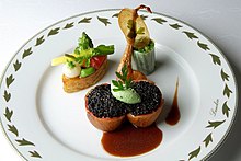 Au centre d'une assiette blanche bordée de feuilles vertes portant la marque du restaurant Lameloise, quatre bouchées. L'une avec des petits pois surmontés d'une sorte de chips, une autre contenant un oignon, un peu de tomate, un mini-poireau surmontés de persil plat. Les deux dernières, accolées, contiennent une sorte de confiture de myrtille, surmontée d'une mousse vert pâle en forme ovoïdale et de persil plat. Deux taches d'une sauce brune achèvent la décoration.