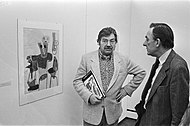 photo of Karel Appel in 1982, with one of his works, in the exhibition 'Works on Paper', Gemeentemuseum Den Haag, Netherlands