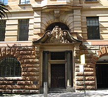 The coat of arms engraved above the building's western entrance, Loftus Street NSW Dept Education Building west side Loftus Street (cropped).JPG