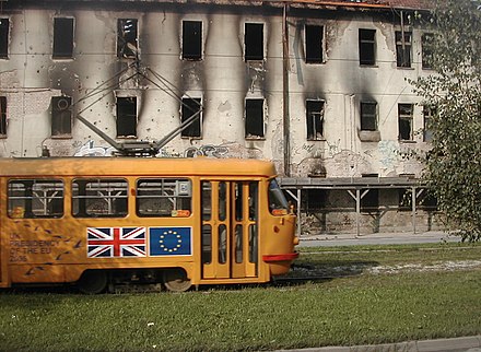 Tramvia donat per la UE davant d'un edifici cremat