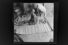 A Poro boy sitting on a matt, while a man is preparing the ritual SierraLeone Hofstra 008.jpg