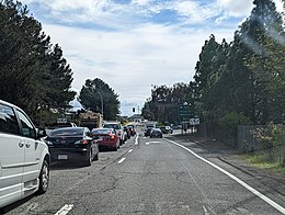 A photo of an intersection with several cars at a red light.