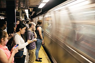 Morning rush hour on the New York City Subway platform at Jackson Heights-Roosevelt Avenue Standing on the Yellow Platform Line.jpg