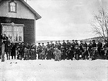 Around 40 troops of the paramilitary Red Guard pose to the camera next to a farmer's house on a field. One of them, their apparent commander, is on a horse.