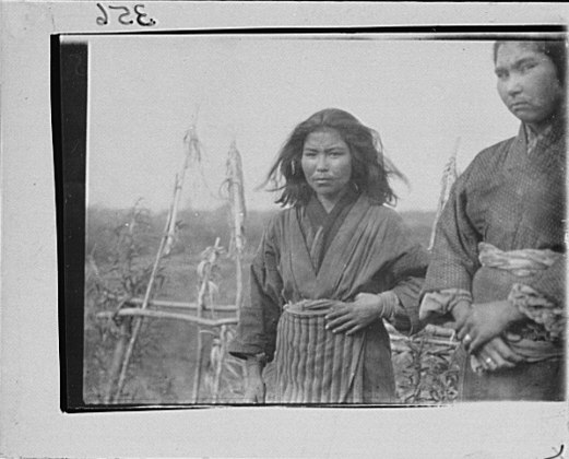 File:Two Ainu women standing outside in front of a pole fence LOC agc.7a10206.tif