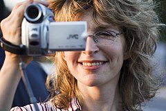 A young smiling woman recording, digital movie camera in hand, Rome, Italy