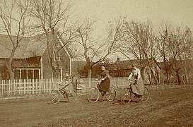 Women on bicycles on unpaved road, USA, late 19th Century