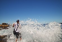 A rip current pouring over the people standing on rock shore at the northern end of Bondi beach (2019)