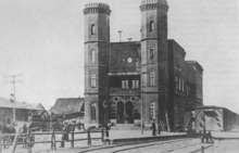 Die Ansicht zeigt den alten Inselbahnhof vor seiner westseitigen Erweiterung 1866 mit den beiden achteckigen Türmen und dem gusseisernen Haupteingang auf der Ostseite (um etwa 1860). Rechts neben dem Empfangsgebäude befindet sich der Perron der Sächsisch-Schlesischen Eisenbahn, links der der Niederschlesisch-Märkischen Eisenbahn.