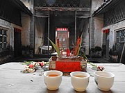 中国での祖先崇拝の例。先祖が住んでいた古い家で、お茶と線香などを供物としてささげている。