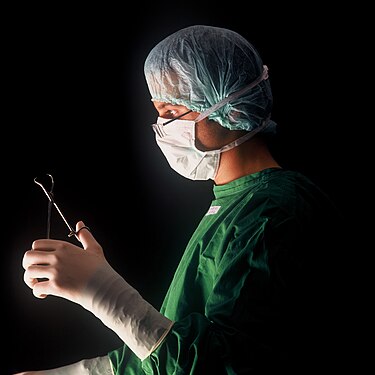 Surgeon with surgical mask and surgical forceps in a hospital in Germany