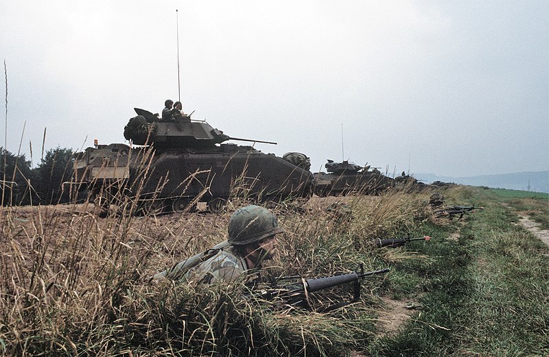 File:DA-ST-86-00224 Three M2 Bradley advance through a wooded area during Exercise REFORGER '85.jpeg