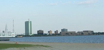 Downtown Lake Charles from a beach on the opposite side of Lake Charles (the lake). A casino riverboat, Harrah's Pride of Lake Charles, appears to the left.