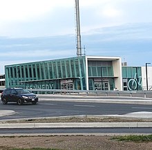 A photo of a glass panelled light rail station with the name "Kennedy" in bold white lettering on the side. The structure is mostly completed, but signage over the entrances has not yet been added.