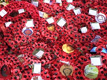 Several wreaths of artificial red poppies with black centres. The logo of various veterans and community groups are printed in the middle of each.