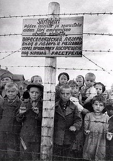 Russian children at a Finnish-run transfer camp in Petrozavodsk. The sign reads, in Finnish and Russian: "Transfer camp. Entry to the camp and conversations through the fence are forbidden under the penalty of death." Konclagers.jpg