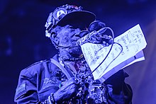 Lee Perry (pictured in 2016) sings in a falsetto voice on Revolution Dub. Lee Scratch Perry 2016 (2 von 11).jpg