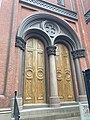 Arched Lombard Romanesque doors with pilasters and Church's logo on top