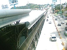 Vista parcial da estação de nível com vários carros ao longo da avenida.