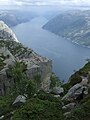 Hier sieht man den Preikestolen von oben mit zahlreichen Touristen und dem Lysefjord im Hintergrund.