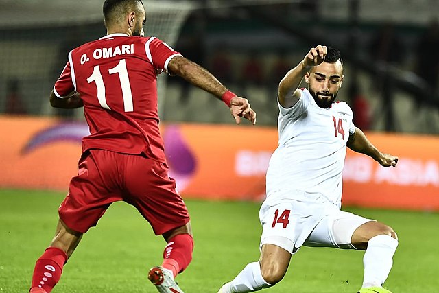 Syria's Osama Omari battling for the ball with Palestine's Abdullah Jaber