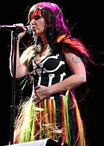 Image d'une chanteuse brune portant une robe composée d'un haut en forme de squelette et d'une jupe de plusieurs couleurs