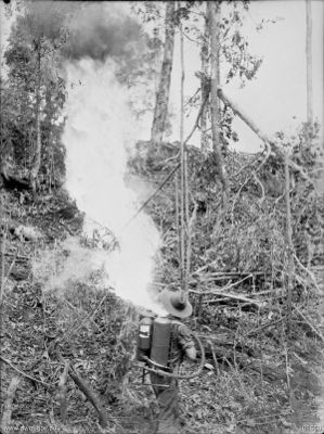 An Australian soldier fires a flamethrower at a Japanese bunker
