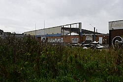 Dubbed an "eyesore" by the local press, a disused Ford dealership and long-closed Esso petrol station, originally known as Crystal Ford before it fell under the nationwide Evans Halshaw Ford banner, closing in 2008 when the Ford business moved elsewhere and falling under numerous owners as a used car dealership until 2019, began to be demolished in September 2023. It is reported that nearby manufacturer of pharmaceuticals Reckitts plans to expand onto the site when demolition is complete. This image depicts a general overview of the dealership site under demolition.