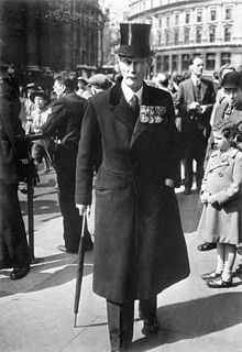 a tall elderly man in formal attire and top hat walking on a city square