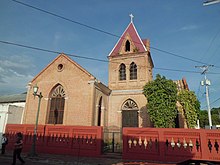 Église en briques rouges surmontée d'une croix celtique