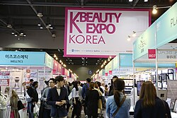 Valokuva K-beauty Exposta Koreassa. Kuvassa on ihmisiä tutkimassa tapahtuman kosmetiikkatarjontaa.