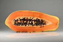 Photograph showing a papaya in cross section, with orange flesh and numerous black seeds