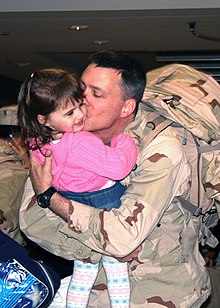 A father kissing the cheek of his daughter US Navy 080210-N-5292M-001 Lt. Robert O'Connell, assigned to Combined Joint Task Force-Horn of Africa (CJTF-HOA), kisses his daughter after returning to the Naval Air Terminal at Naval Station Norfolk.jpg
