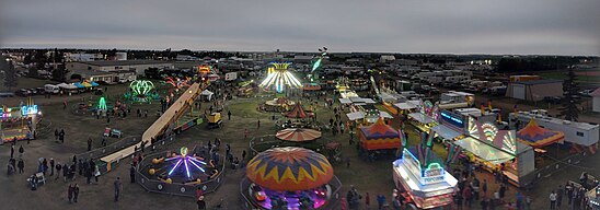 The Midway, as seen at night, lit up by the bright and colourful lights of amusement park rides.