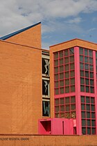 Een oranje bakstenen gebouw met roze raamkozijnen en een blauw dak