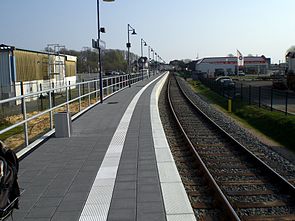 Az új Fehmarn-Burg megálló.  A peron bal oldalán a háttérben a régi vasútállomás épülete látható.