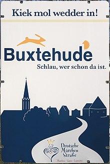 Hinweisschild am Ortseingang von Buxtehude mit Turm der St.-Petri-Kirche (l.) und Marschtorzwinger (r.). Darüber Hase und Igel.