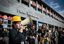 Witalina Kowal ist von Menschen umgeben und trägt einen gelben Helm. Sie spricht in ein Megafon, das sie in der Hand hält.