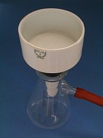 Büchner-Trichter mit eingelegtem runden Filterpapier auf einer Saugflasche mit angeschlossenem Vakuumschlauch