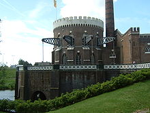 Bâtiment rond en brique d'architecture gothique avec poutres en acier dépassant des fenêtres