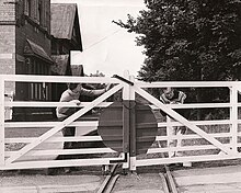 Volunteers from the Supporters' Association repainting the crossing gates at Port St. Mary Station in July 1973; until the nationalisation of the line in 1978 the Association maintained an active volunteer presence on the railway, both operationally by providing guards and gatekeepers, and peripheral works such as painting and maintenance at the lineside; these efforts were later concentrated on their restoration of the Groudle Glen Railway PSM-Gates.jpg