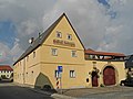 Gasthof mit Hauptgebäude (Nr. 10), winkelförmig angebautem Rückgebäude (Nr. 10a) und Seitengebäude sowie Einfriedungsmauer und Toranlage (Torbogen und Pforte)