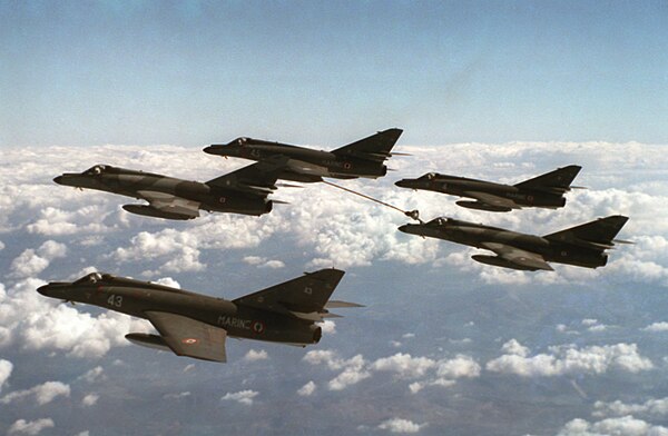 A formation of Super Étendards in flight, one of which is refueling another Super Étendard, through "buddy-to-buddy" refueling process.