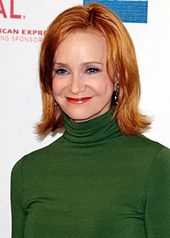 A color photograph of Swoosie Kurtz, a woman with blue eyes and brown-red hair, in a green sweater