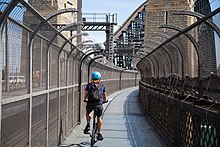 A cyclist using the cycleway. Side fences were added to prevent people from committing suicide by jumping from the bridge. Sydney Harbour Bridge cyclist.jpg