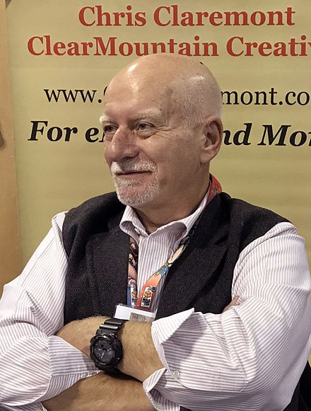 Claremont seated and smiling with his arms crossed