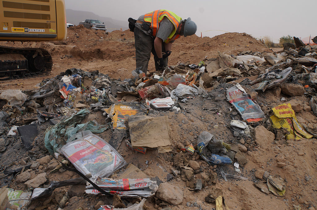 Un homme travaille, sur un amoncellement de déchets Atari retrouvés lors de l'excavation qui s'est déroulée en 2014, mêlés à divers papiers, plastiques, des gravas et de la terre, jonchant le sol de la déchetterie de la ville d'Alamogordo.