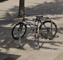 Bicycle locked to a stand in a street, London Bicycle stand in a street, London.png